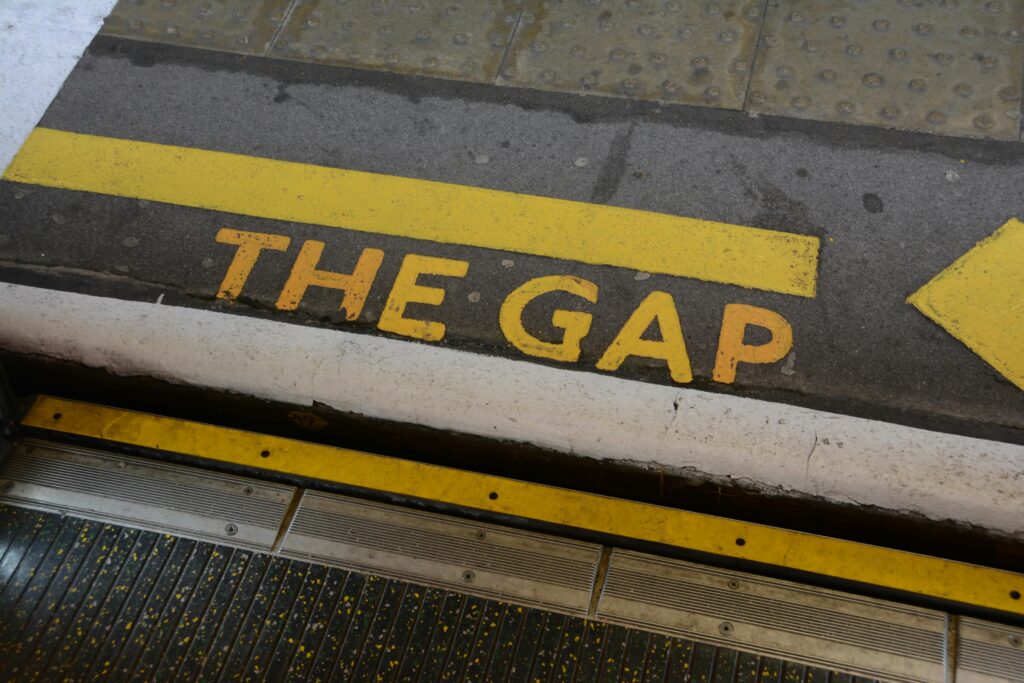 Close-up of 'Mind the Gap' warning sign on station platform edge, focusing on safety.
